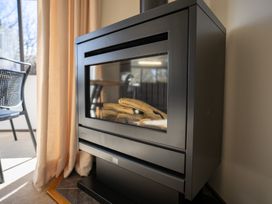 A fireplace with a chair in a living room at Te Anau - Holiday Home