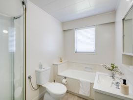 A bathroom with a shower, bathtub, toilet, and sink at Havelock North Holiday Home