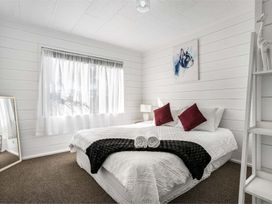 A bedroom with a bed and mirror at Whitianga Holiday Home in Whitianga