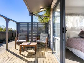 An outdoor patio with wooden chairs and a small table at Whitianga Holiday Home in Whitianga
