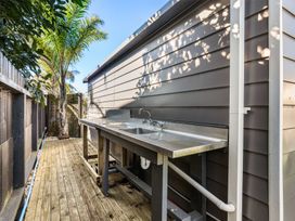 An outdoor kitchen area with a sink and wooden deck at Whitianga Holiday Home in Whitianga