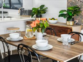 A dining room with a table set and flowers at Whitianga Holiday Home in Whitianga