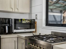 A kitchen with a microwave and air fryer on the countertop at Whitianga Holiday Home in Whitianga