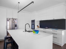 A kitchen with an island, sink, refrigerator and stove at Tindall's Beach in Whangaparaoa Peninsula