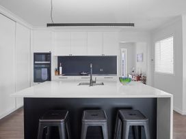 A kitchen with a sink and kitchen island at Tindall's Beach Whangaparaoa Peninsula