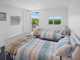 A bedroom with two beds and windows at Tindall's Beach Whangaparaoa Peninsula