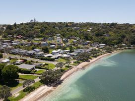 An aerial view of a beach with houses along the shore at Tindall's Beach Whangaparaoa Peninsula