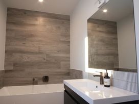 A bathroom with a bathtub and sink at Tindall's Beach, Whangaparaoa Peninsula