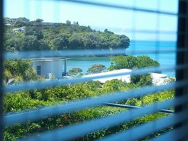A view of trees and water from behind window blinds at Tindall's Beach Whangaparaoa Peninsula