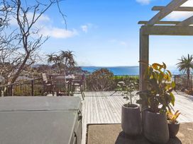 An outdoor area with a table and chairs overlooking the sea at Red Beach Retreat - Whangaparaoa Peninsula