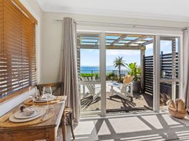 A dining area with a view of the outdoor seating at Red Beach Retreat - Whangaparaoa Peninsula