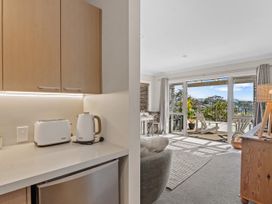 A kitchen area with appliances and entrance to a living space at Red Beach Retreat - Whangaparaoa Peninsula