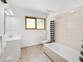 A bathroom with a sink, toilet, bathtub, and window at Paihia