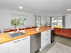 A kitchen featuring a sink, dishwasher, and dining table at Ruakaka Coastal Reserve Retreat Ruakaka