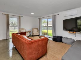 A living room with a sofa and armchairs at Ruakaka Coastal Reserve Retreat in Ruakaka