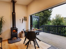 A dining room with a stove, table, and chairs at Hidden Springs Mountain View Waihi