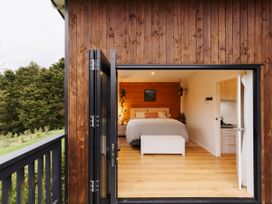 A bedroom with a bed and kitchen area at Hidden Springs Mountain View Waihi