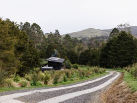 A house surrounded by trees and a gravel road at Hidden Springs Mountain View Waihi