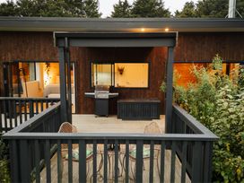 A deck with a barbecue grill and outdoor furniture at Hidden Springs Mountain View Waihi