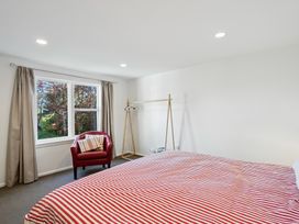 A bedroom with a bed and armchair at Wanaka Holiday Home in Wanaka