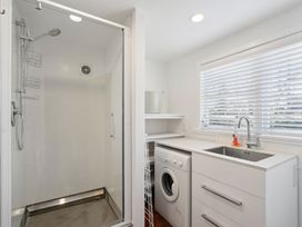 A laundry area with a shower and washing machine at Wanaka Holiday Home in Wanaka