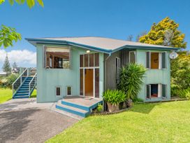 A house with a front porch and garden at Whangamata