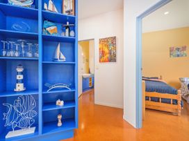 A hallway with a blue bookshelf and a view of a bedroom at Whangamata