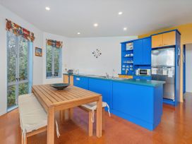 A kitchen with a wooden dining table and appliances at Whangamata