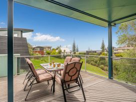 An outdoor deck with chairs and a table at Whangamata