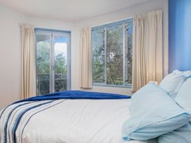 A bedroom with a bed and windows at Whangamata