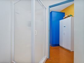 A bathroom with a shower and cabinets at Whangamata