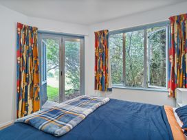 A bedroom with a bed and windows at Whangamata