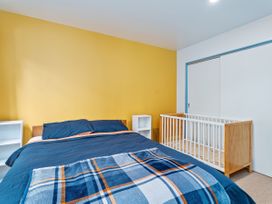 A bedroom with a bed and a crib at Whangamata