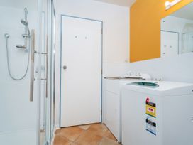 A laundry room with a shower and washing machine at Whangamata