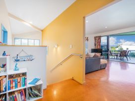 A living room with a bookshelf, couch, and sliding glass door at Whangamata