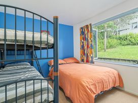 A bedroom with a bunk bed and a double bed at Whangamata in Whangamata