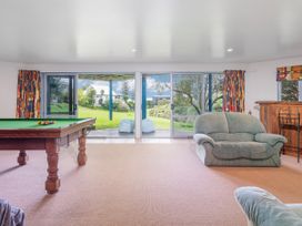A game room with a pool table and sliding doors leading to a garden at Whangamata
