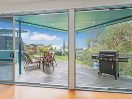 An outdoor balcony with a table and chairs and a barbecue grill at Whangamata