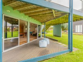 An outdoor area with a deck, table, and seating at Whangamata, Whangamata