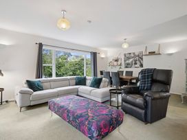 A living room with a sofa, ottoman, and dining area at Khandallah Stays - Wellington