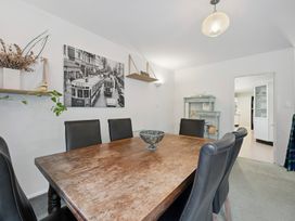 A dining room with a wooden table and black chairs at Khandallah Stays - Wellington