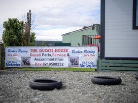 A sign for The Ducati House with services and contact info at Ducati House - Te anau Holiday Home