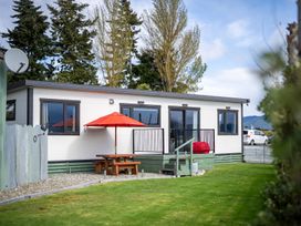 An outdoor area with a house, table, and red umbrella at Ducati House - Te anau Holiday Home