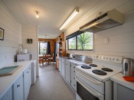 A kitchen with a stove and refrigerator at The Back Hut - Te Anau Holiday Home