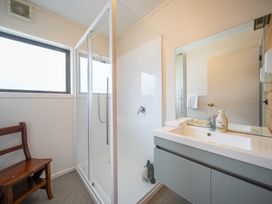 A bathroom with a shower and vanity at The Back Hut - Te Anau Holiday Home in Te Anau