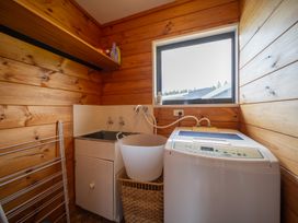 A laundry room with a washing machine and a sink at The Back Hut - Te Anau Holiday Home