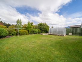 A garden with a greenhouse and clothesline at The Back Hut - Te Anau Holiday Home Te Anau