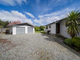 A property exterior with a garage and driveway at The Back Hut - Te Anau Holiday Home