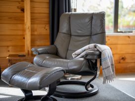 A chair and footrest with a blanket at The Back Hut - Te Anau Holiday Home Te Anau