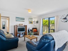 A living room with a sofa and television at Kapiti Breeze - Waikanae Beach Holiday Home